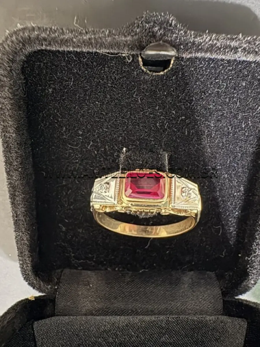 Anel em ouro 14K amarelo e branco, com 2cm de diâmetro interno, com duas incrustações de diamante sobre o ouro branco e um rubi sintético centralizado sobre o ouro amarelo, com massa de 2,9 g