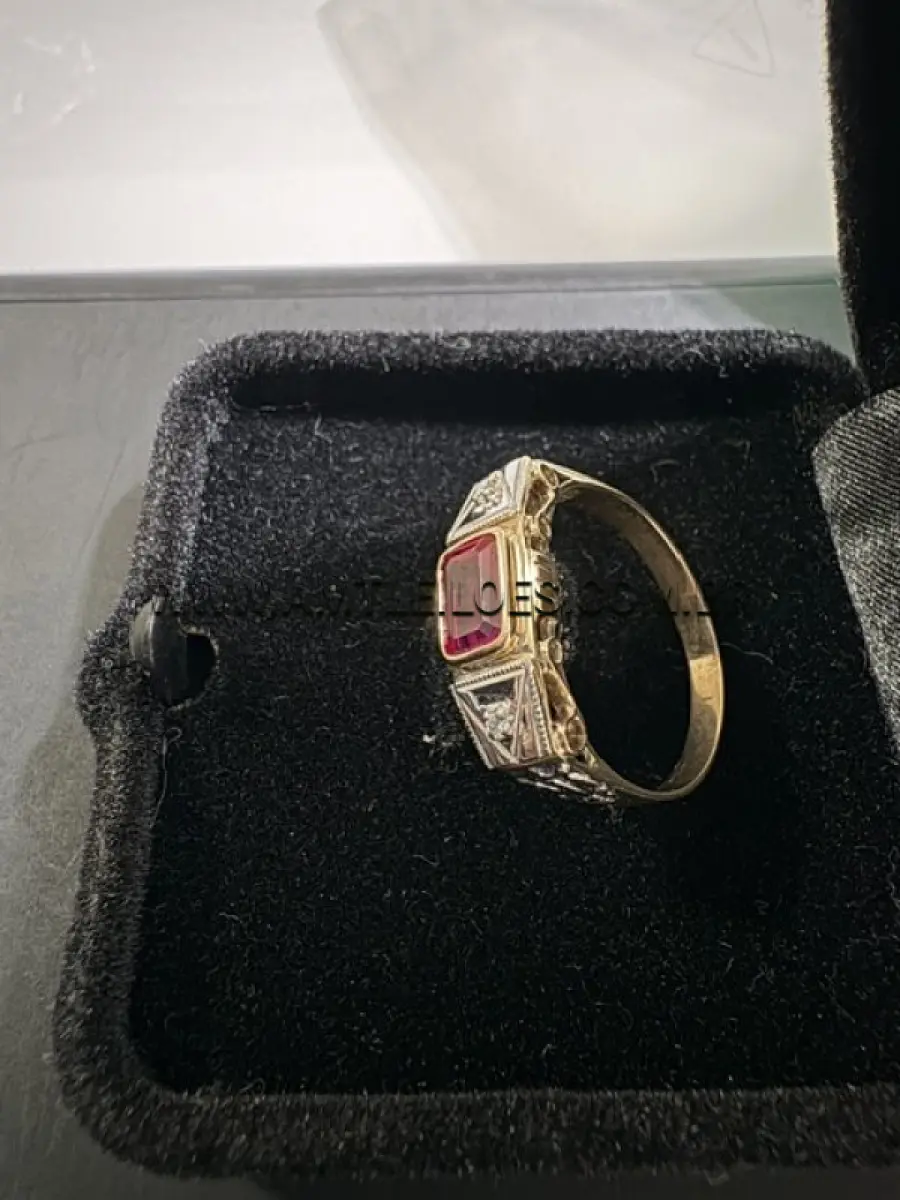 LOTE 016 - Anel em ouro 14K amarelo e branco, com 2cm de diâmetro interno,  com duas incrustações de diamante sobre o ouro branco e um rubi sintético centralizado  sobre o ouro amarelo, com massa de 2,9 g..