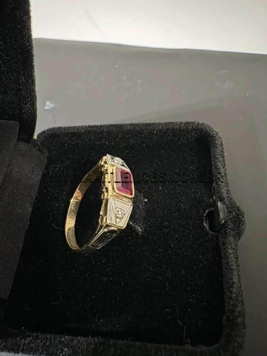 LOTE 016 - Anel em ouro 14K amarelo e branco, com 2cm de diâmetro interno,  com duas incrustações de diamante sobre o ouro branco e um rubi sintético centralizado  sobre o ouro amarelo, com massa de 2,9 g..